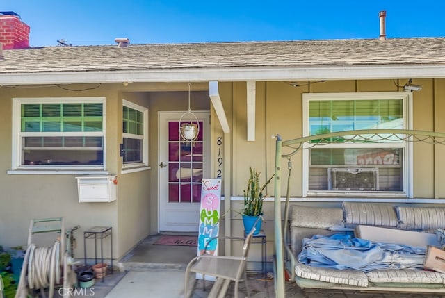 8192 Ashgrove Dr, La Mirada, CA 90638 - view of exterior entry featuring roof with shingles, a chimney, stucco siding, a porch, and cooling unit