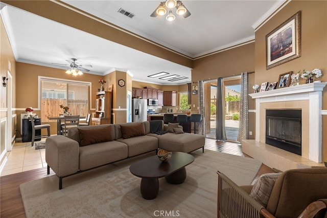 2802 Silver Shore Ln, Bakersfield, CA 93313 - living area featuring ornamental molding, light wood-type flooring, plenty of natural light, ceiling fan, and a tiled fireplace