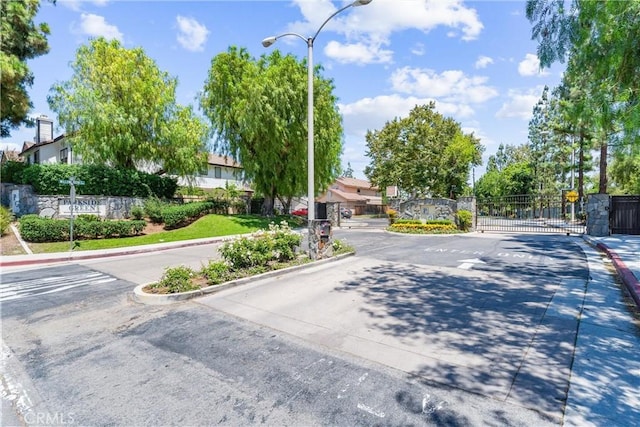 861 Shade Tree Way, Corona, CA 92878 - view of asphalt road featuring a gate, curbs, a gated entry, street lighting, and traffic signs