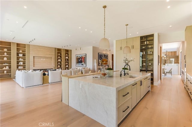 16711 Moorpark St, Encino, CA 91436 - kitchen with built in features, a large island with sink, modern cabinets, light wood finished floors, and light stone counters