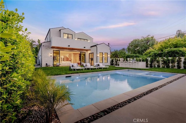 16711 Moorpark St, Encino, CA 91436 - back of property at dusk featuring a balcony, an outdoor pool, a patio area, an outdoor hangout area, and stucco siding