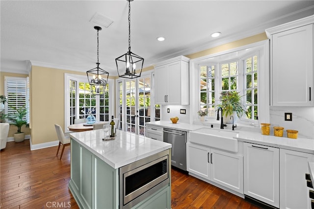 42 Fairlane Rd, Laguna Niguel, CA 92677 - kitchen featuring appliances with stainless steel finishes, crown molding, white cabinets, dark wood finished floors, and hanging light fixtures