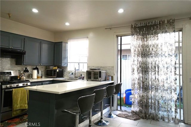 18347 Saticoy St Unit 33, Reseda, CA 91335 - kitchen with appliances with stainless steel finishes, under cabinet range hood, a peninsula, tasteful backsplash, and healthy amount of natural light