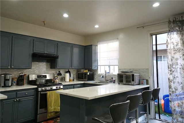 18347 Saticoy St Unit 33, Reseda, CA 91335 - kitchen featuring stainless steel appliances, under cabinet range hood, a peninsula, backsplash, and healthy amount of natural light
