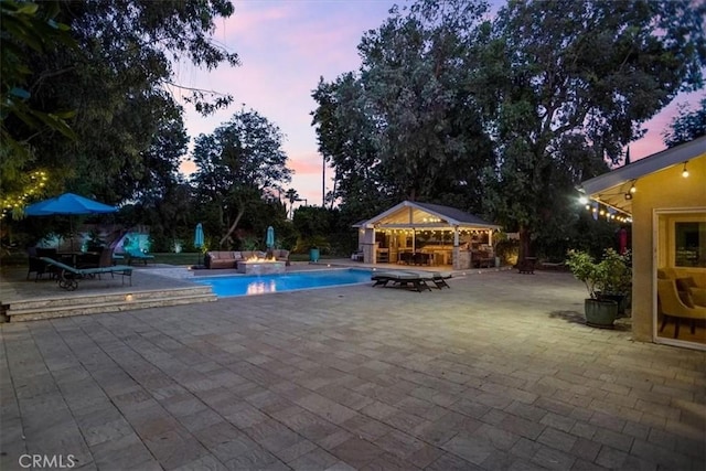 10624 Nevada Ave, Chatsworth, CA 91311 - pool at dusk with a storage structure, an outdoor pool, a patio, and an outdoor structure