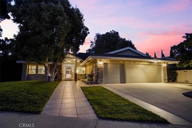 10624 Nevada Ave, Chatsworth, CA 91311 - ranch-style home featuring concrete driveway, stone siding, an attached garage, and a lawn