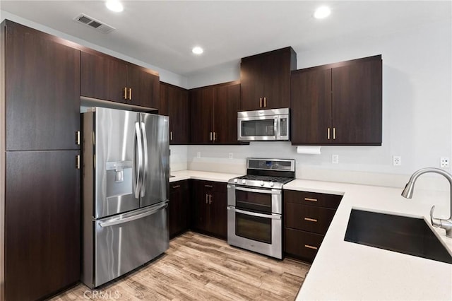 5 Zacate St, Rancho Mission Viejo, CA 92694 - kitchen with stainless steel appliances, light countertops, dark brown cabinetry, light wood-style flooring, and recessed lighting