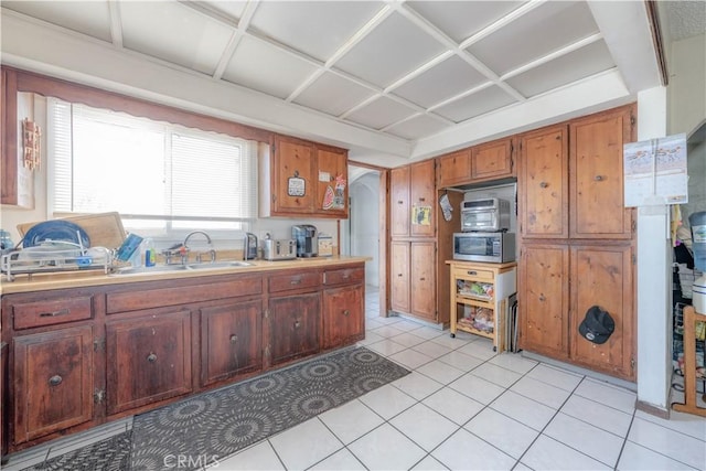13572 Sutter Dr, Westminster, CA 92683 - kitchen with stainless steel microwave, arched walkways, light countertops, light tile patterned floors, and brown cabinets