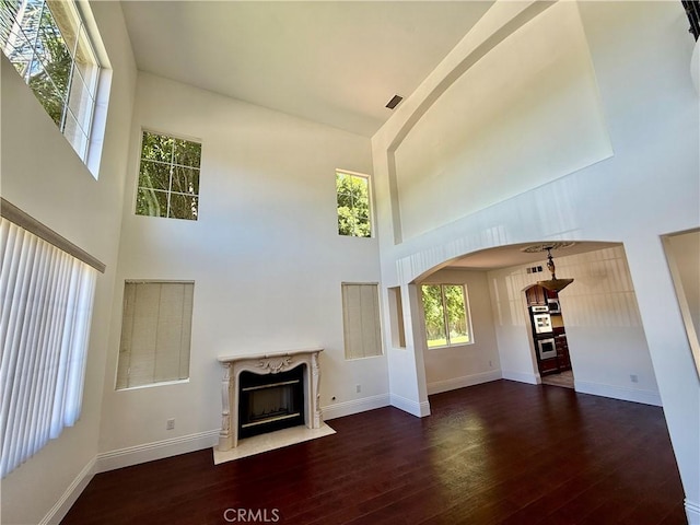11737 Lois Ct, Granada Hills, CA 91344 - unfurnished living room featuring a towering ceiling, wood-type flooring, arched walkways, and a high end fireplace