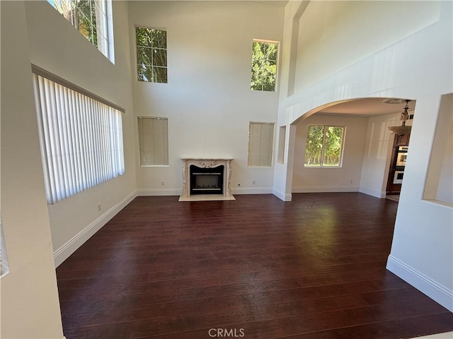 11737 Lois Ct, Granada Hills, CA 91344 - unfurnished living room with a towering ceiling, arched walkways, dark wood-type flooring, and a fireplace