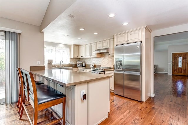 2580 Crown Way, Fullerton, CA 92833 - kitchen with appliances with stainless steel finishes, under cabinet range hood, a peninsula, recessed lighting, and light wood-style flooring