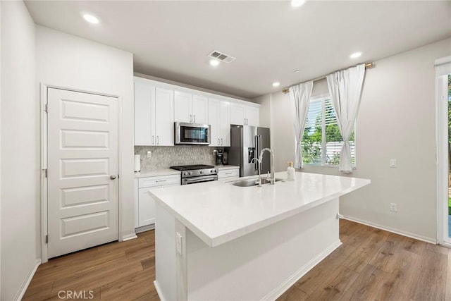 247 Lockhart Way, West Covina, CA 91790 - kitchen featuring appliances with stainless steel finishes, a kitchen island with sink, light wood finished floors, white cabinetry, and recessed lighting