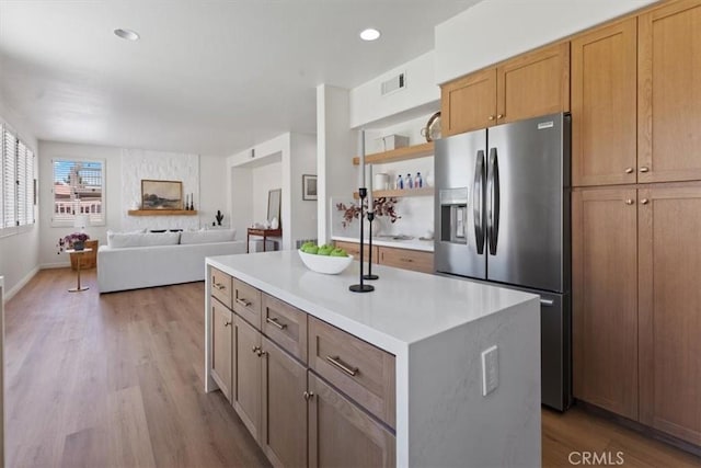 14080 Crestline Pl, Rancho Cucamonga, CA 91739 - kitchen featuring stainless steel fridge, light wood-style flooring, open shelves, a center island with sink, and light countertops