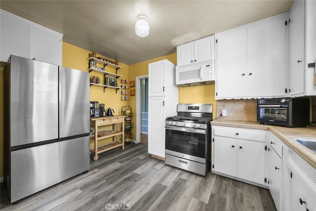2184 S Towne Ave, Pomona, CA 91766 - kitchen with stainless steel appliances, light countertops, light wood-style flooring, and white cabinets