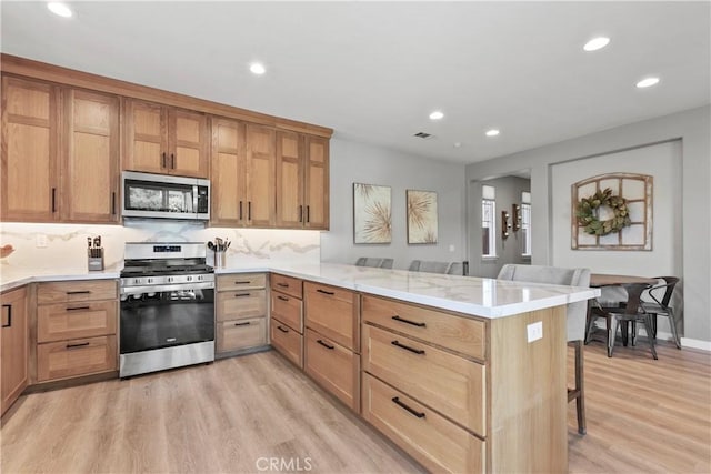 9180 Araujo Ct, Atascadero, CA 93422 - kitchen featuring appliances with stainless steel finishes, a peninsula, light wood-style flooring, recessed lighting, and a kitchen breakfast bar