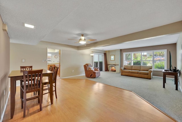 6820 Hyde Park Dr Unit A, San Diego, CA 92119 - dining area featuring a textured ceiling, a ceiling fan, light wood finished floors, a brick fireplace, and light colored carpet