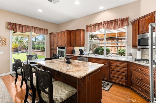 14067 Glendale Ct, Rancho Cucamonga, CA 91739 - kitchen with stainless steel appliances, light wood-type flooring, decorative backsplash, a center island, and recessed lighting