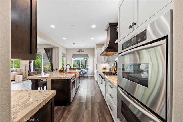 982 Camino Del Arroyo Dr Unit 49, San Marcos, CA 92078 - kitchen featuring wall chimney exhaust hood, light stone counters, dark wood finished floors, recessed lighting, and stainless steel appliances