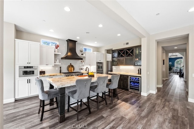 982 Camino Del Arroyo Dr Unit 49, San Marcos, CA 92078 - kitchen featuring beverage cooler, ventilation hood, tasteful backsplash, dark wood-type flooring, and a kitchen breakfast bar