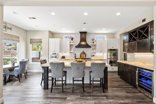 982 Camino Del Arroyo Dr Unit 49, San Marcos, CA 92078 - kitchen with wine cooler, double oven, custom exhaust hood, open shelves, and backsplash