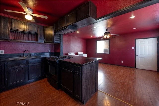8933 Locust Ave, Fontana, CA 92335 - kitchen with black range with gas cooktop, a ceiling fan, washing machine and dryer, dark countertops, and wood finished floors