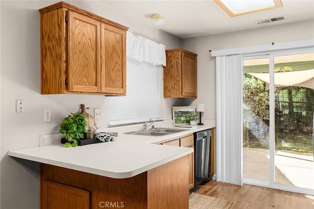 1057 Windsor Way, Chico, CA 95926 - kitchen with stainless steel dishwasher, a peninsula, light countertops, light wood-style flooring, and brown cabinets