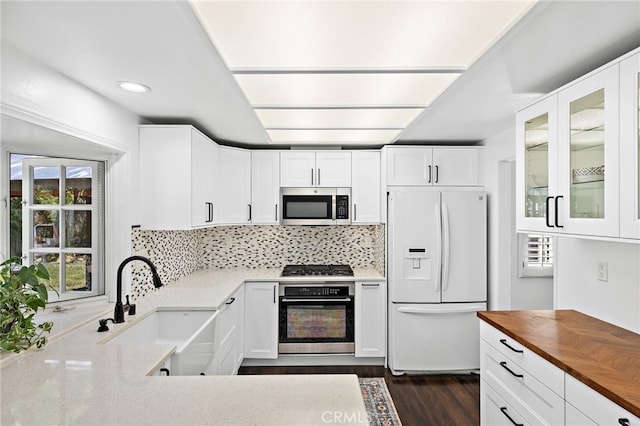 24802 La Plata Dr, Laguna Niguel, CA 92677 - kitchen with stainless steel appliances, butcher block counters, glass insert cabinets, white cabinetry, and backsplash