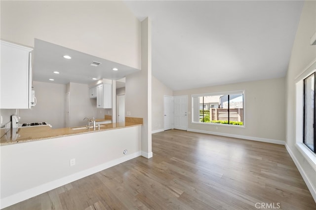 17842 Beard Ln Unit 88, Huntington Beach, CA 92647 - kitchen featuring light wood-style floors, white cabinetry, light countertops, high vaulted ceiling, and a peninsula