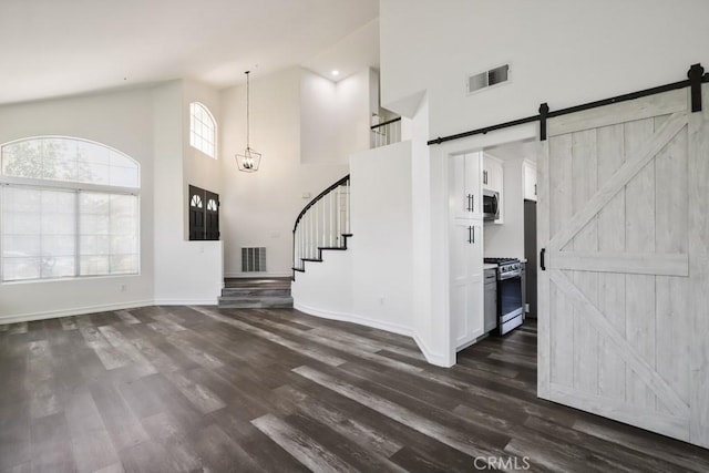 14226 Remington Ct, Fontana, CA 92336 - unfurnished living room with a high ceiling, a barn door, dark wood-type flooring, and stairway