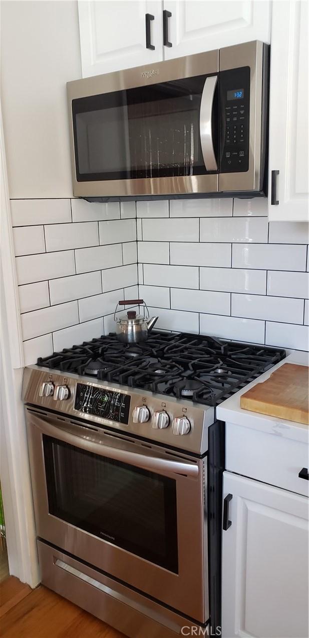 4131 Perlita Ave Unit B, Los Angeles, CA 90039 - kitchen with appliances with stainless steel finishes, white cabinets, backsplash, and light countertops