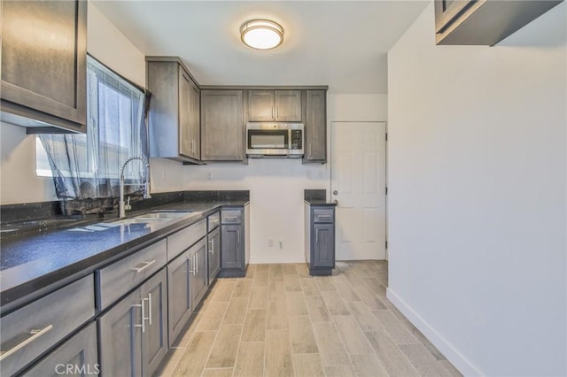 1026 W 109th St, Los Angeles, CA 90044 - kitchen with stainless steel microwave, light wood finished floors, and dark brown cabinets