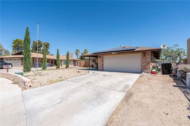 1267 Joshua Tree Dr, Barstow, CA 92311 - ranch-style house with solar panels, concrete driveway, stone siding, and an attached garage