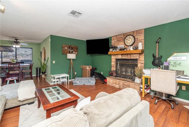 1267 Joshua Tree Dr, Barstow, CA 92311 - living area with a textured ceiling, a stone fireplace, a ceiling fan, and wood finished floors