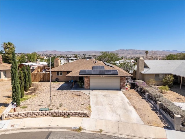 1267 Joshua Tree Dr, Barstow, CA 92311 - view of front of house with an attached garage, roof mounted solar panels, concrete driveway, and a mountain view