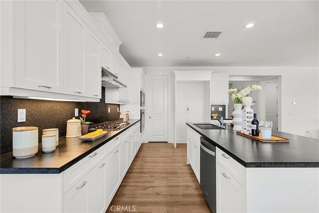 19162 Lauren Ln, Saugus, CA 91350 - kitchen with dark countertops, appliances with stainless steel finishes, under cabinet range hood, a center island with sink, and backsplash