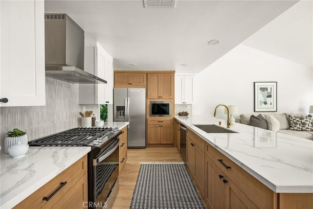 16917 Eric Ave, Cerritos, CA 90703 - kitchen featuring stainless steel appliances, wall chimney exhaust hood, a peninsula, light wood-style flooring, and light stone counters