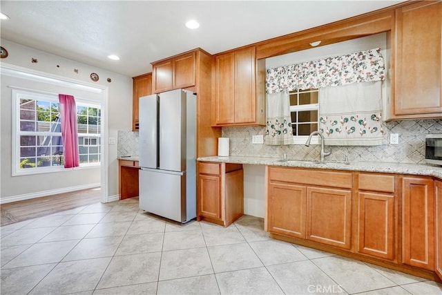 8084 Magnolia Ave, Riverside, CA 92504 - kitchen featuring freestanding refrigerator, backsplash, brown cabinets, recessed lighting, and light stone counters