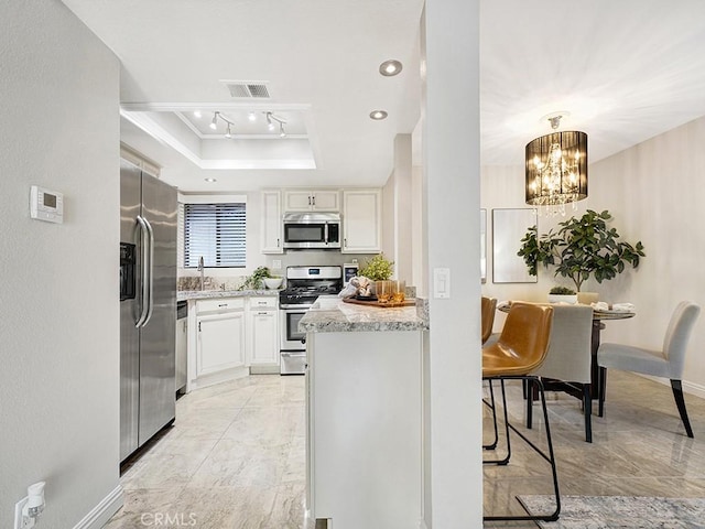 28191 Sorrento Unit 111, Laguna Niguel, CA 92677 - kitchen featuring stainless steel appliances, a raised ceiling, white cabinets, a chandelier, and recessed lighting