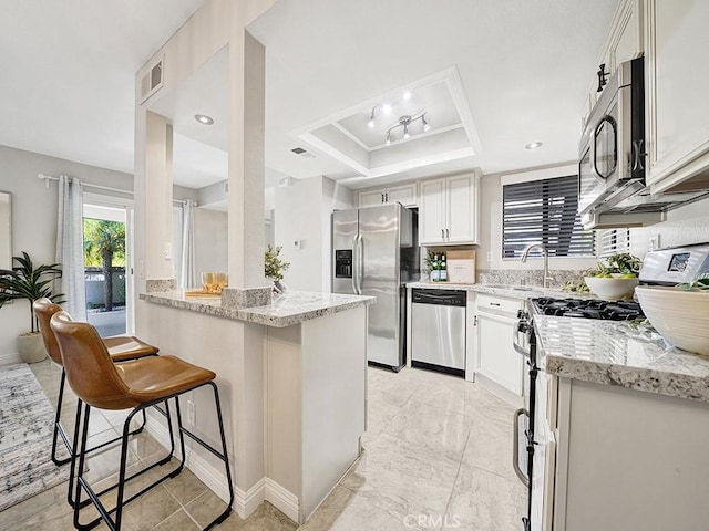 28191 Sorrento Unit 111, Laguna Niguel, CA 92677 - kitchen with stainless steel appliances, a breakfast bar area, light stone counters, a peninsula, and a raised ceiling