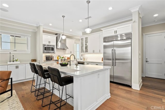 716 Elvira Ave Unit A, Redondo Beach, CA 90277 - kitchen with built in appliances, wall chimney range hood, ornamental molding, backsplash, and white cabinetry