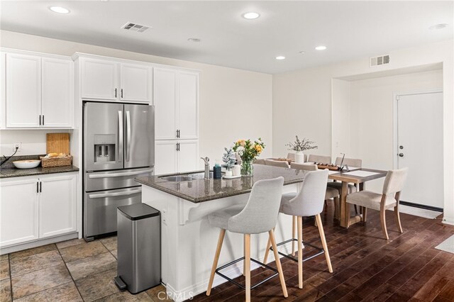 8495 E Preserve Loop, Chino, CA 91708 - kitchen featuring stainless steel refrigerator with ice dispenser, a kitchen island with sink, white cabinetry, a breakfast bar, and dark stone counters