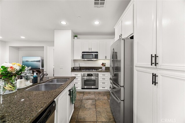8495 E Preserve Loop, Chino, CA 91708 - kitchen with appliances with stainless steel finishes, white cabinets, recessed lighting, dark stone counters, and dark stone finish flooring