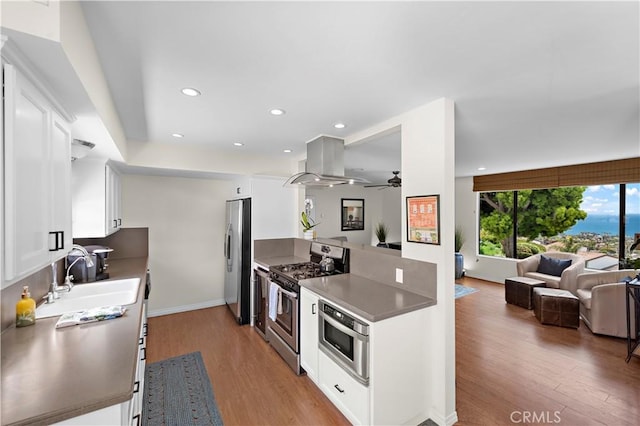 100 Calle Patricia Unit 1A, San Clemente, CA 92672 - kitchen with island range hood, stainless steel appliances, open floor plan, light wood-style flooring, and recessed lighting