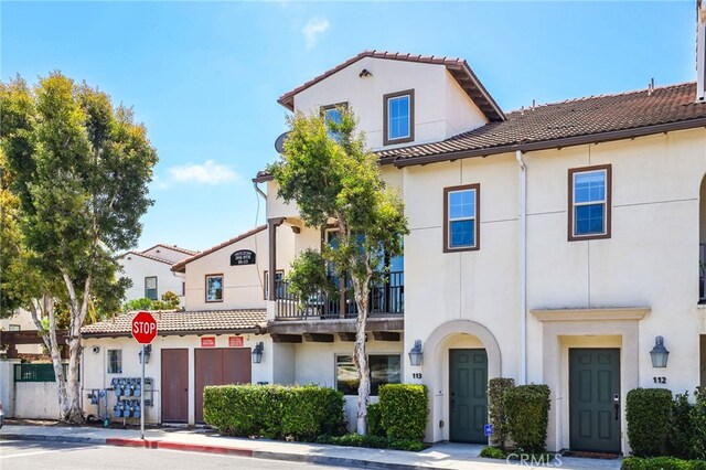 2950 19th St Unit 113, Signal Hill, CA 92707 - view of front facade with a tiled roof, stucco siding, and a balcony