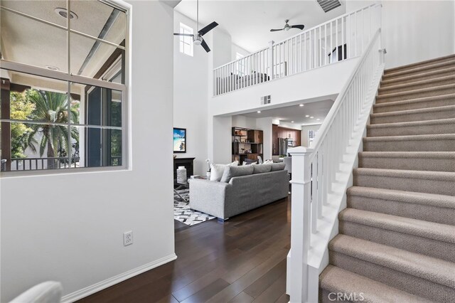 2950 19th St Unit 113, Signal Hill, CA 92707 - stairway featuring a ceiling fan, healthy amount of natural light, wood finished floors, and a towering ceiling