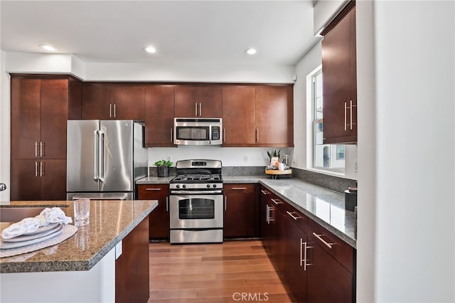 2950 19th St Unit 113, Signal Hill, CA 92707 - kitchen featuring appliances with stainless steel finishes, wood finished floors, stone countertops, recessed lighting, and dark brown cabinets