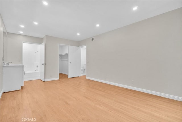 600 W 3rd St Unit C207, Santa Ana, CA 92701 - unfurnished bedroom featuring a walk in closet, light wood-type flooring, ensuite bath, and recessed lighting