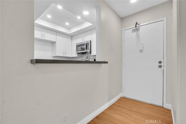 600 W 3rd St Unit C207, Santa Ana, CA 92701 - kitchen with stainless steel microwave, light wood-style flooring, recessed lighting, white cabinetry, and a raised ceiling