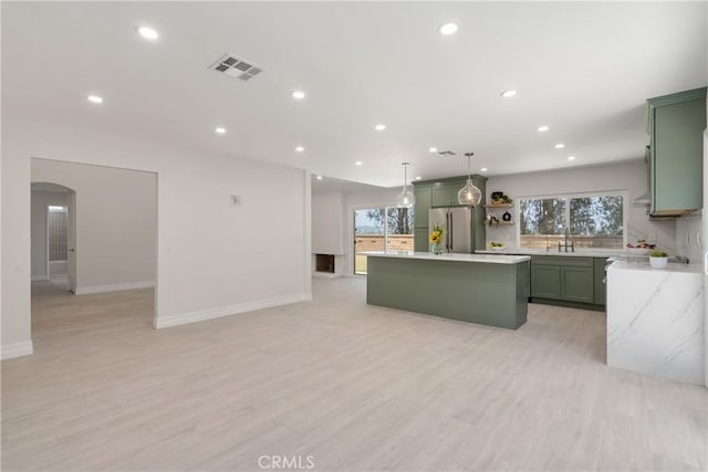 22 Sage Cyn, Pomona, CA 91766 - kitchen with freestanding refrigerator, green cabinetry, a kitchen island, recessed lighting, and arched walkways