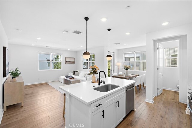 944 N Divino Privado Unit 57, Ontario, CA 91764 - kitchen with dishwasher, open floor plan, decorative light fixtures, a center island with sink, and light wood-style flooring